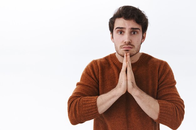 close-up portrait of worried and sad young handsome man asking for help, begging you forgive him