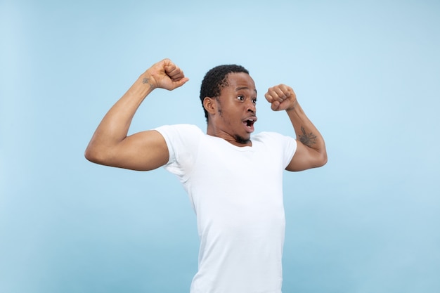 Free photo close up portrait of young african-american man in white shirt. human emotions, facial expression, ad, concept. celebrating, wondered, astonished, shocked, crazy happy.