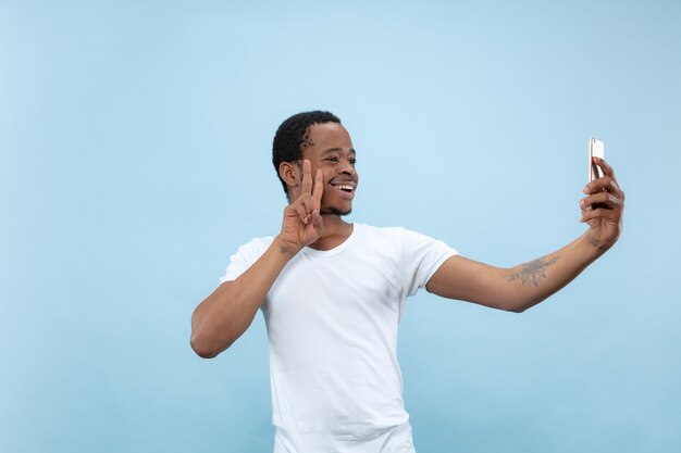 close up portrait of young african-american man in white shirt.. Making selfie or content for social media, vlog.