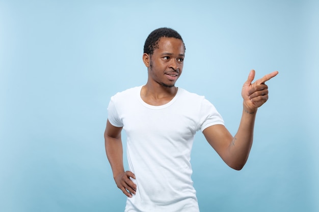 close up portrait of young african-american man in white shirt.. Pointing, choosing and smiling.