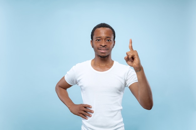 close up portrait of young african-american man in white shirt.. Showing empty bar, pointing, choosing, inviting.