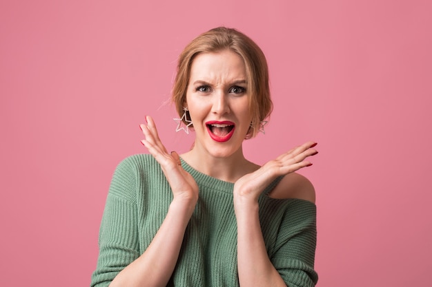 Free photo close up portrait of young attractive woman with shocked face expression, surprised, emotional, funny, isolated on pink background, holding hands up, open mouth, happy, looking in camera