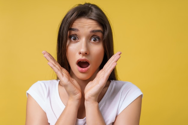 Free photo close up portrait young beautiful attractive student girl shocking with something bright yellow background copy space