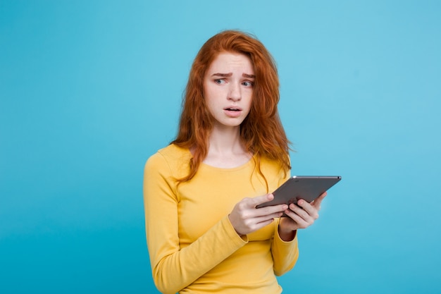 Close up Portrait young beautiful attractive tender ginger redhair girl happy smiling on digital table with wining something. Blue Pastel Background. Copy space.