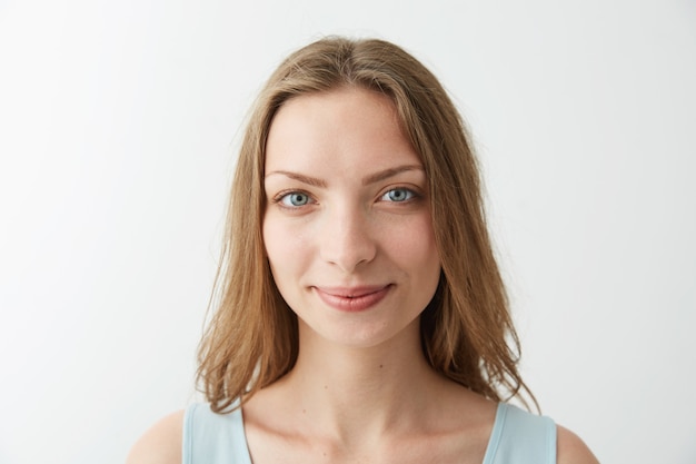 Close up portrait of young beautiful blonde girl with blue eyes smiling .