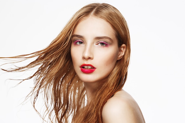 Close-up portrait of young beautiful girl with flying hair and bright make up. white wall. Isolated.