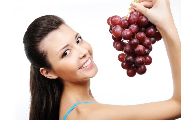 Close-up portrait of young beautiful happy woman with bunch of grapes