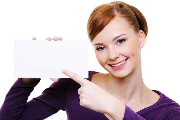 Close-up portrait of Young caucasian smiling girl pointing on the blank white card