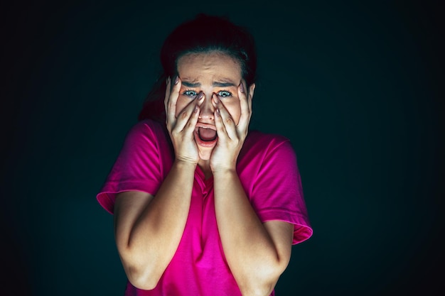 Free photo close up portrait of young crazy scared and shocked woman isolated on dark