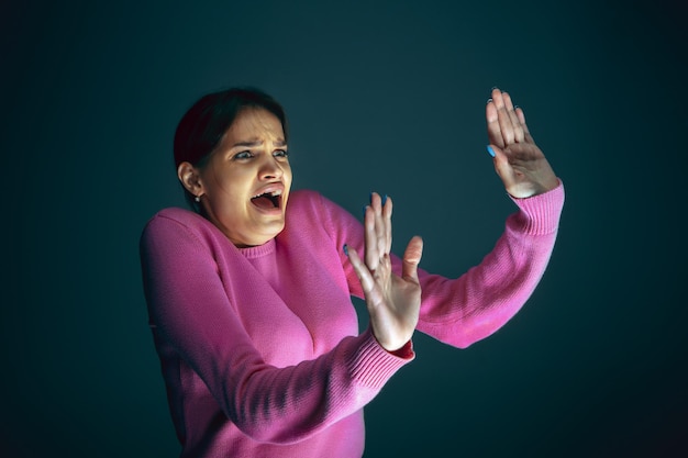 Close up portrait of young crazy scared and shocked woman isolated on dark