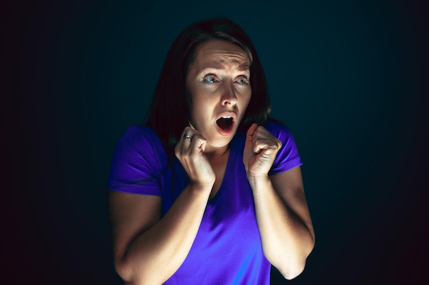 Close up portrait of young crazy scared and shocked woman isolated on dark