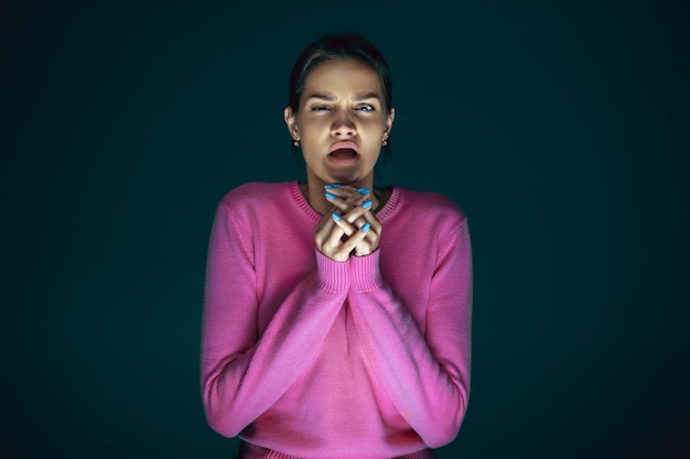 Close up portrait of young crazy scared and shocked woman isolated on dark