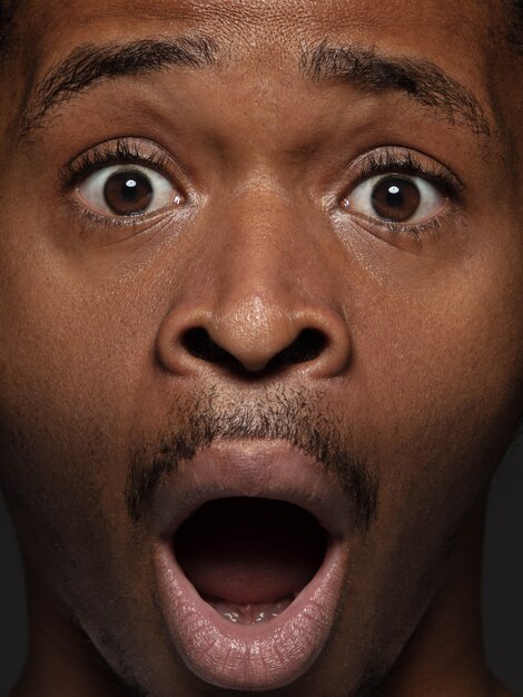 Close up portrait of young and emotional african-american man. Highly detail photoshot of male model with well-kept skin and bright facial expression. Concept of human emotions. Astonished, shocked.