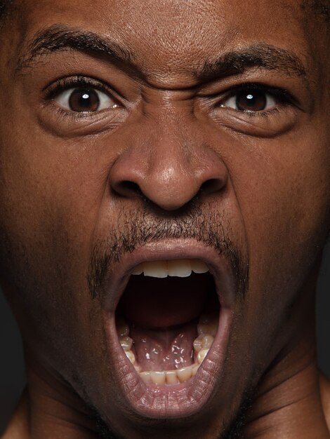 Close up portrait of young and emotional african-american man. male model with well-kept skin and bright facial expression. Concept of human emotions. Angry screaming.