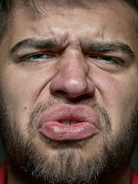 Foto gratuita close up ritratto di giovane ed emotivo uomo caucasico. molto dettagliato del modello maschile con pelle ben tenuta e un'espressione del viso luminosa. concetto di emozioni umane. sensazione disgustosa.