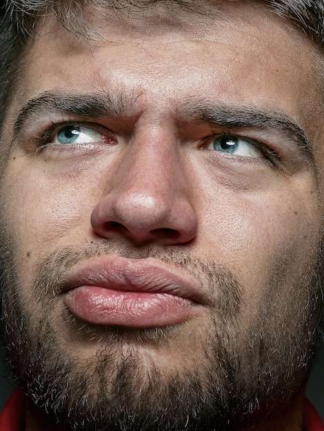 Close up portrait of young and emotional caucasian man. Highly detail photoshot of male model with well-kept skin and bright facial expression. Concept of human emotions. Thinking angry.