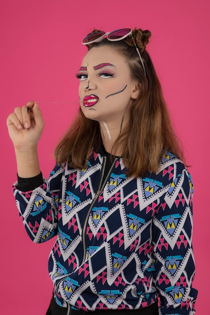 Close up portrait of young girl wearing creative makeup and looking at camera while chewing gum. High quality photo