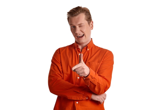 Close-up portrait of a young good-looking ginger peson in a stylish orange shirt gesticulating and looking at the camera while posing isolated on white studio background. Human facial expressions. Sin