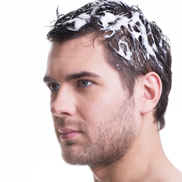 Крупным планом портрет молодой красавец мытье волос с шампунем - изолированные на белом.