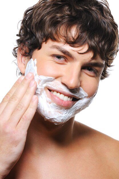 Free photo close-up portrait of young happy man's face with shaving cream