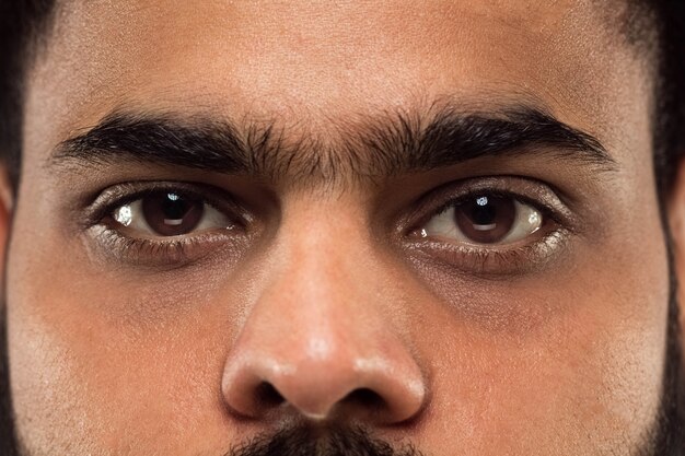 Close up portrait of young hindoo man's face with brown eyes looking right at camera