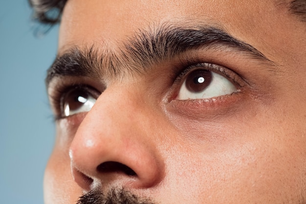 Close up portrait of young indian man's face with brown eyes looking up or at side. Human emotions, facial expression. Looking dreaming or hopeful.