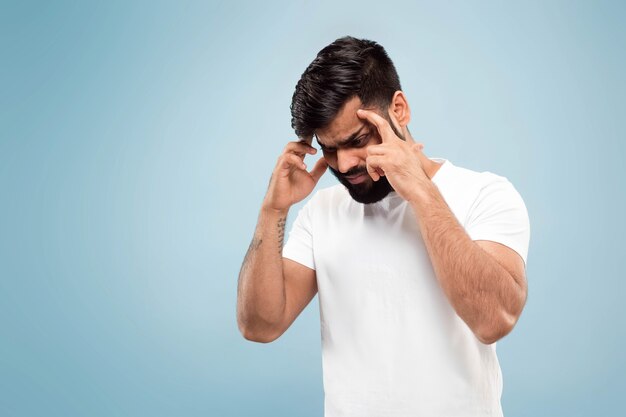 close up portrait of young indian man in white shirt.  Concentrating, suffering from headache.