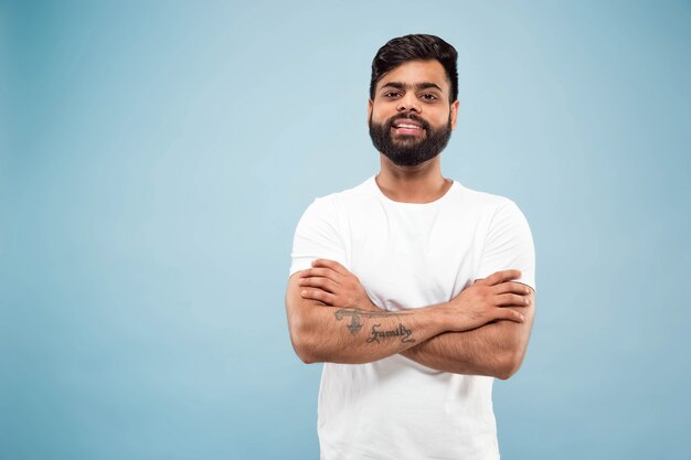 close up portrait of young indian man in white shirt.  Posing, standing and smiling, looks calm.