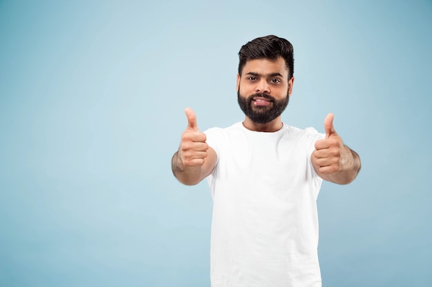 close up portrait of young indian man in white shirt.  Showing the sign of OK, nice, great. Smiling.