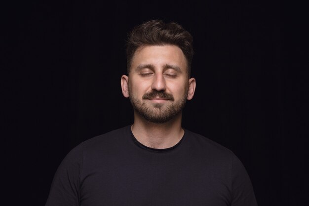 Close up portrait of young man on black studio