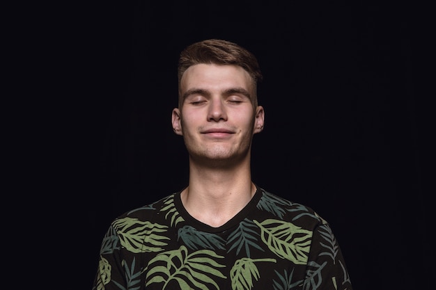 Close up portrait of young man isolated on black  space.  Thinking and smiling