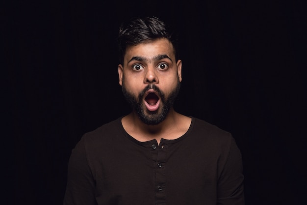 Close up portrait of young man isolated on black studio background. Photoshot of real emotions of male model. Wondering, exciting and astonished. Facial expression, human emotions concept.