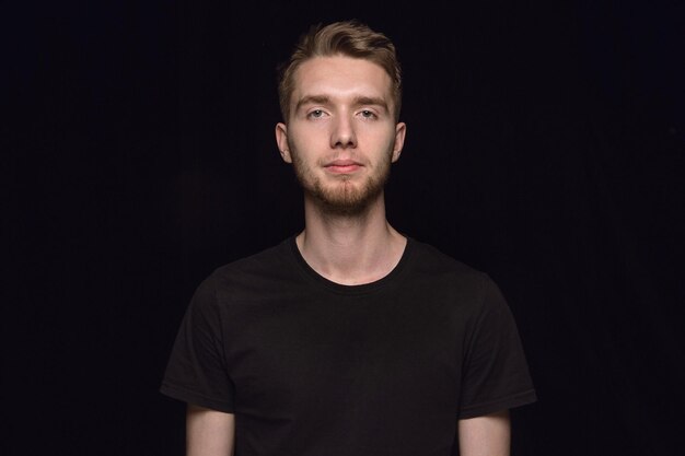 Close up portrait of young man isolated on black studio background