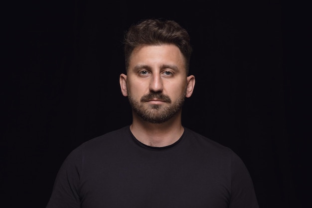 Close up portrait of young man isolated on black studio background