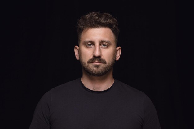 Close up portrait of young man isolated on black studio background