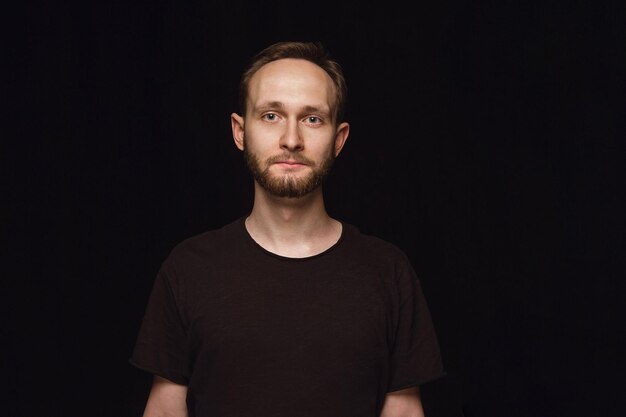 Close up portrait of young man isolated on black studio background