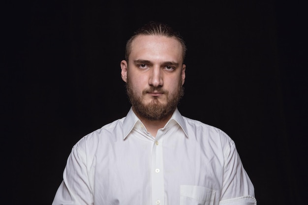 Close up portrait of young man isolated on black studio background