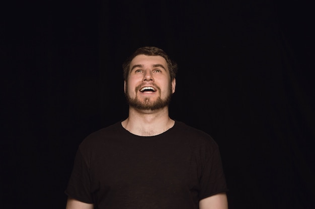 Close up portrait of young man isolated on black studio background.