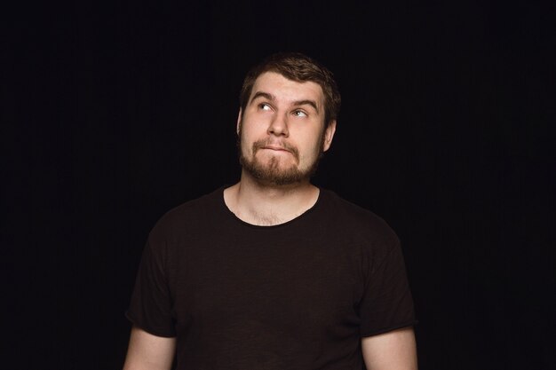 Close up portrait of young man isolated on black studio background.