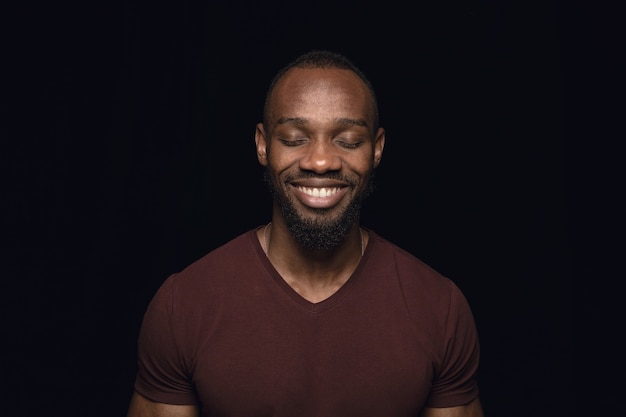 Close up portrait of young man isolated on black studio wall