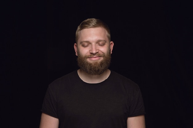 Free photo close up portrait of young man isolated on black studio wall