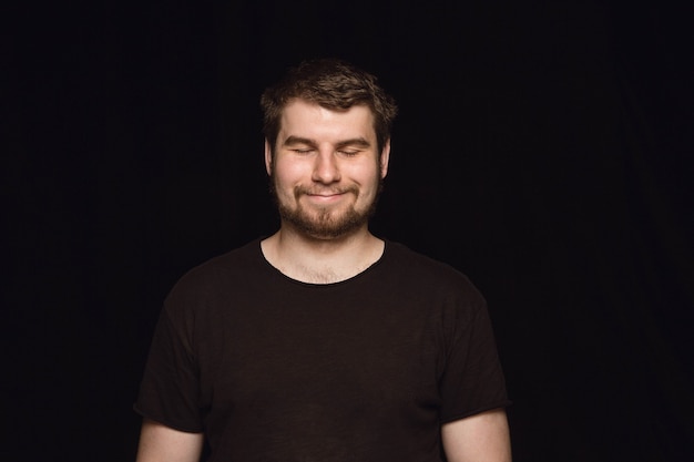 Close up portrait of young man isolated on black studio wall