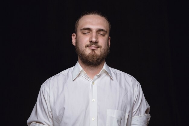 Close up portrait of young man isolated on black studio wall