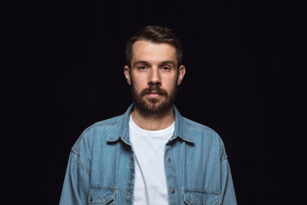 Close up portrait of young man isolated on black studio