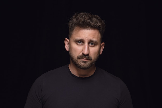 Close up portrait of young man isolated on black studio