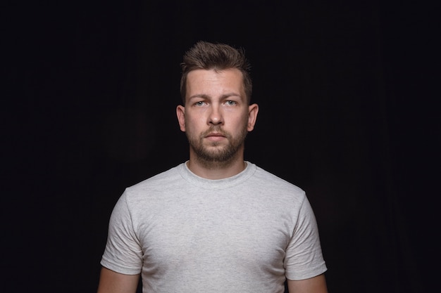 Close up portrait of young man isolated on black studio