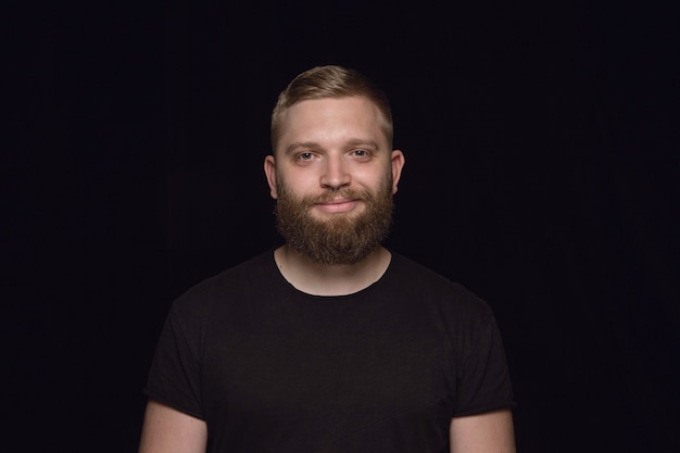 Close up portrait of young man isolated on black studio