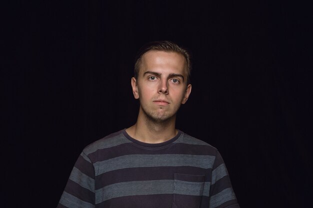 Close up portrait of young man isolated on black wall