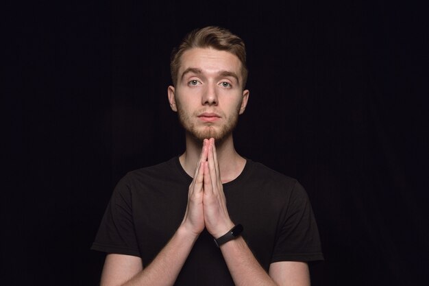 Close up portrait of young man isolated. Praying looking forward, sad and hopeful. Facial expression, human emotions concept.