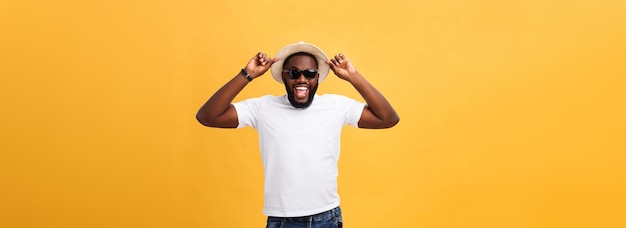 Free photo close up portrait of a young man laughing with hands holding hat isolate over yellow background